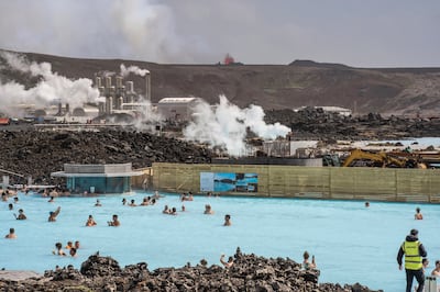 People bathe in the Blue Lagoon in Iceland as a volcanic crater spews lava in the background in Grindavik, Iceland. AP 