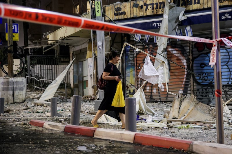 A woman walks past a damaged site after a rocket landed in Tel Aviv. Reuters
