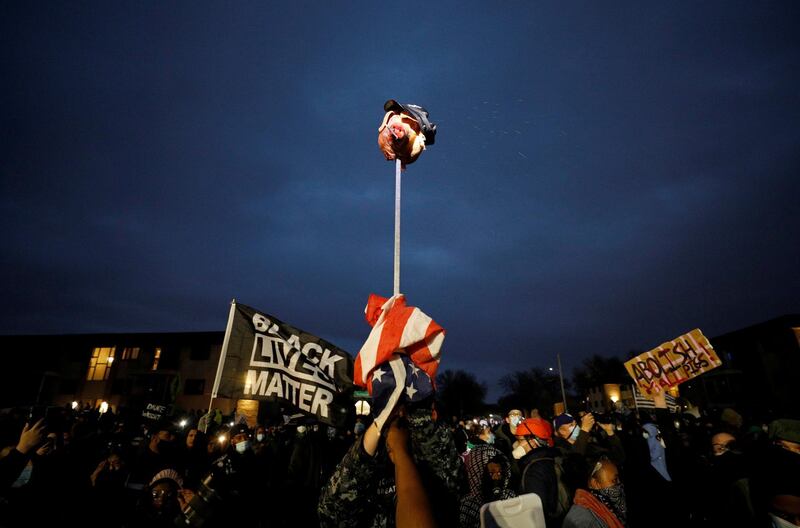 Protesters hold up a pig's head wearing a police cap on a stick outside the Brooklyn Center Police Department, in the US, as protests continue days after former police officer Kim Potter fatally shot Daunte Wright. Reuters