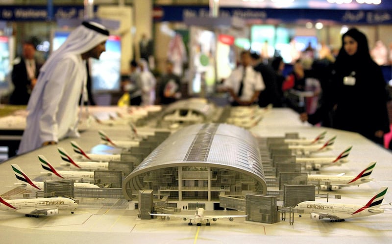 Emiratis look at a model of the new Dubai airport, which is expected to be ready in August 2007, cost 4.1 million USD dollars, and receive 70 billion passengers a year, at the Dubai Air Show 21 November 2005. Authorities in the booming city boast that the ninth edition of the Dubai show, which was last held in 2003, will be 25 percent bigger this year, with nearly 10,000 square meters (108,000 square feet) more exhibition space. AFP PHOTO/RABIH MOGHRABI (Photo by RABIH MOGHRABI / AFP)