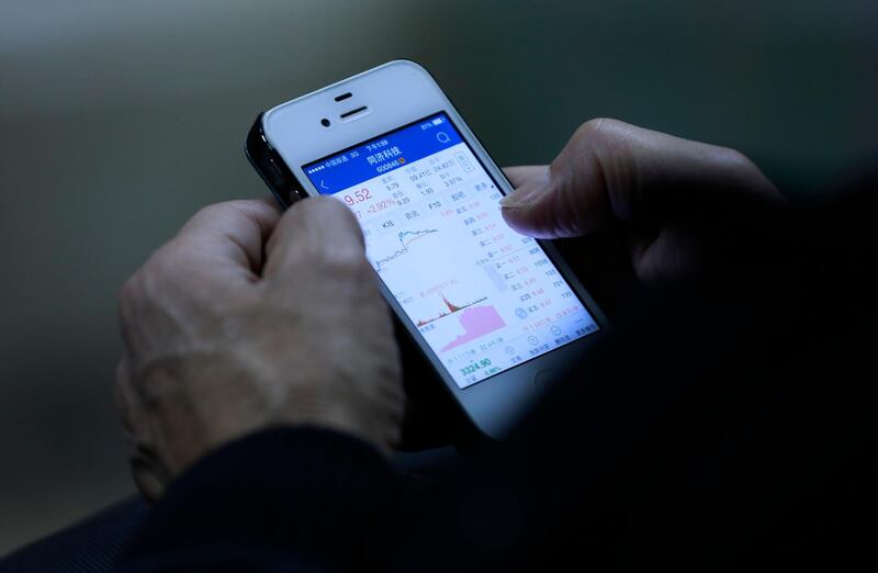 epa06353338 A man looks at stock market movements on his mobile phone at a securities brokerage in Beijing, China, 27 November 2017. China's stock markets fell steeply on 27 November, furthering last week's sell off due to rising borrowing costs and more regulatory measures on financing risks.  EPA/HOW HWEE YOUNG