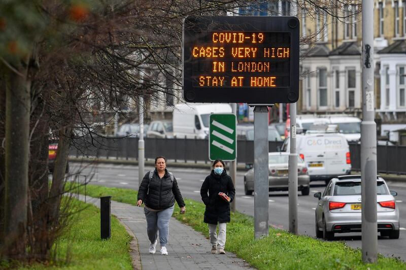 People walk past a roadside public health information sign in London. Reuters