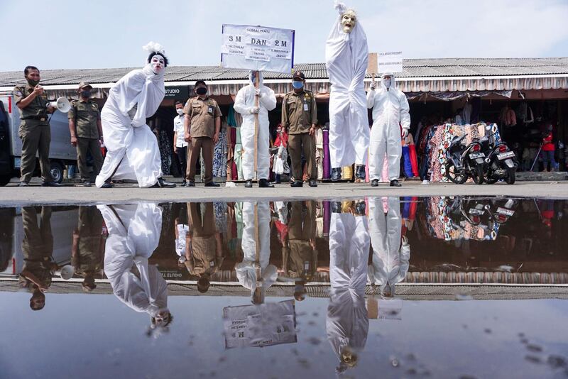 Local government officials wear costumes of pocong, one of the famous ghost figures in Indonesia, in order to campaign for the dangers of the COVID-19 coronavirus, at a traditional market in Tangerang Banten province. AFP