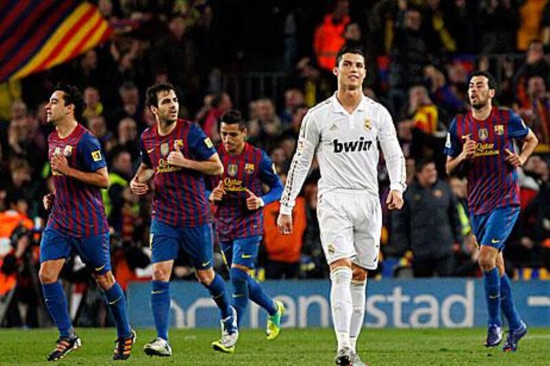 Barcelona players celebrate as Real Madrid's Cristiano Ronaldo looks on in despair.