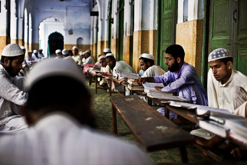 students in an outdoor classroom study and read the Koran at the Darul Uloom Madrassa in Deoband, India