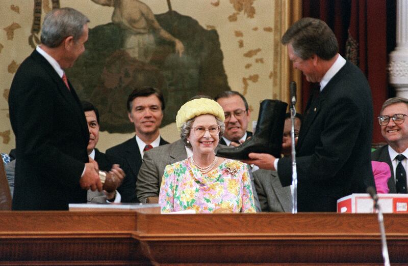 Queen Elizabeth smiles as she is shown a pair of boots in Austin, Texas, on May 20, 1991. AFP