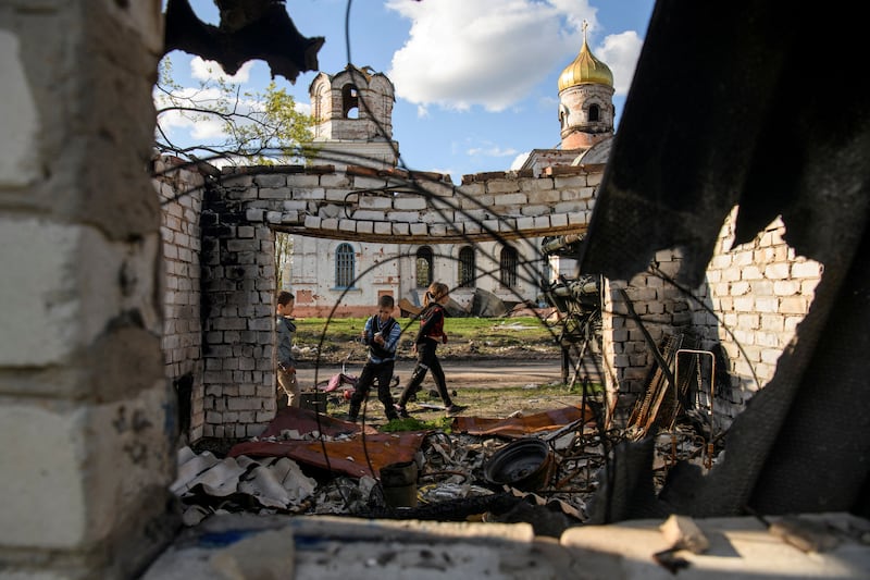 Youngsters Faddei and Oleksandr play in front of a church damaged during Russia's invasion of Ukraine, in the Chernihiv region. Reuters
