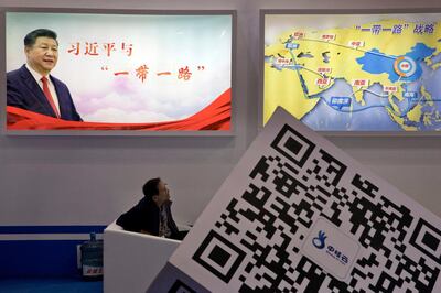 FILE - In this April 28, 2017, file photo, an attendee at a conference looks up near a portrait of Chinese President Xi Jinping with the words "Xi Jinping and One Belt One Road" and "One Belt One Road strategy," in Beijing. Seventy-five years after Japan's surrender in World War II, and 30 years after its economic bubble popped, the emergence of a 21st century Asian power is shaking up the status quo. As Japan did, China is butting heads with the established Western powers, which increasingly see its growing economic and military prowess as a threat. (AP Photo/Ng Han Guan, File)