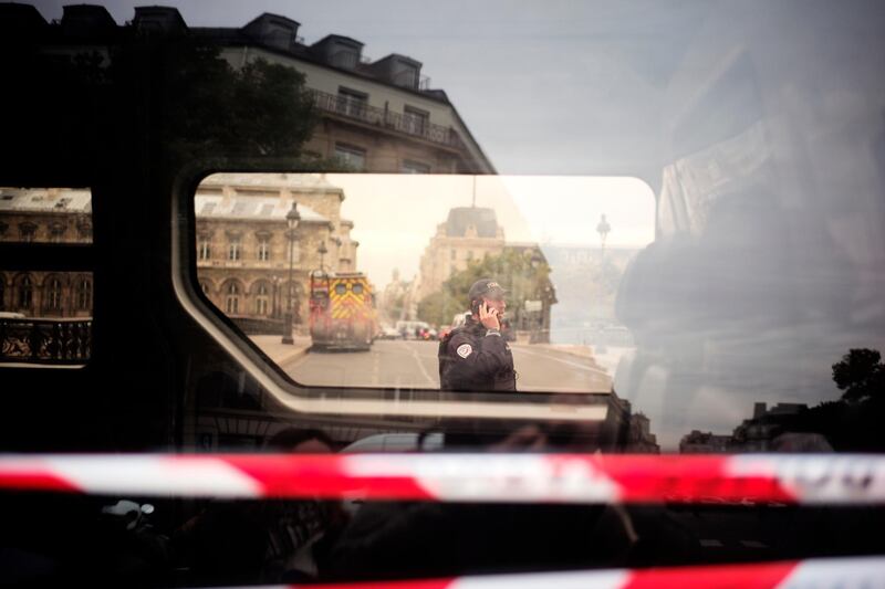A police officer uses his phone near the Paris police headquarters. AP Photo