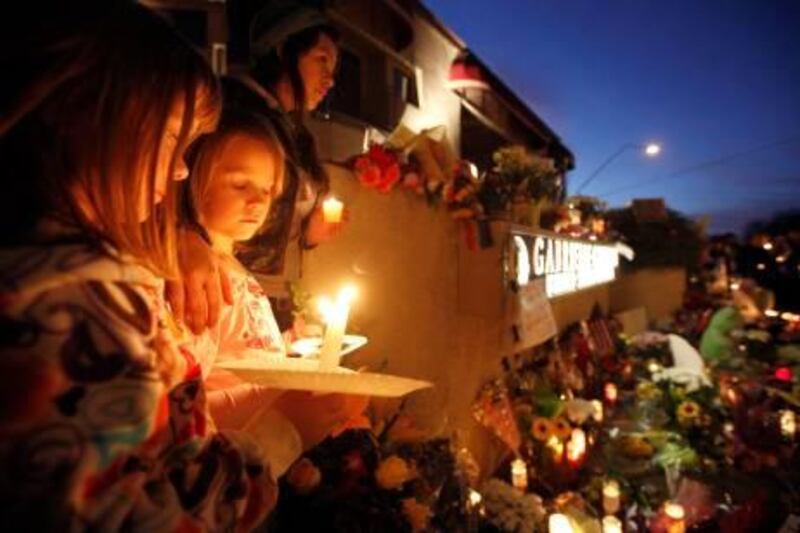 From left, Ellie Steve, 6, Lucia Reeves, 6, and Zoe Reeves, 18, gather for a candlelight vigil outside the offices U.S. Rep. Gabrielle Giffords, D-Ariz., in Tucson, Ariz., Sunday, Jan. 9, 2011. Giffords was critically wounded during a shooting at a political event Saturday in Tucson. (AP Photo/Chris Carlson) *** Local Caption ***  AZCC123_APTOPIX_Congresswoman_Shot_.jpg