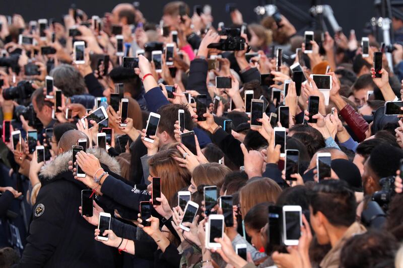 People use their smartphone to take photos of the L'Oreal fashion show on the Champs Elysees avenue during a public event organized by French cosmetics group L'Oreal as part of Paris Fashion Week, France, October 1, 2017.  REUTERS/Charles Platiau