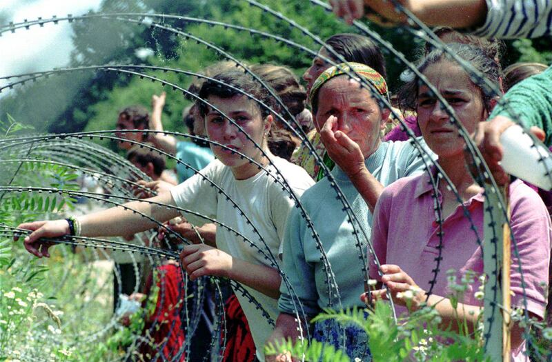Refugees from Srebrenica look through the razor-wire at a UN base outside Tuzla on July 13, 1995. AP Photo