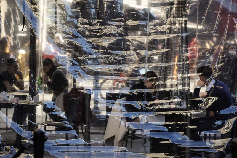 People enjoy a drink at a cafe in Milan, Italy. AP Photo