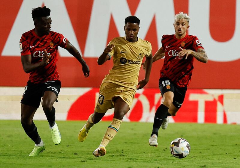 Barcelona forward runs with the ball between Mallorca players Iddrisu Baba and Pablo Maffeo. Reuters