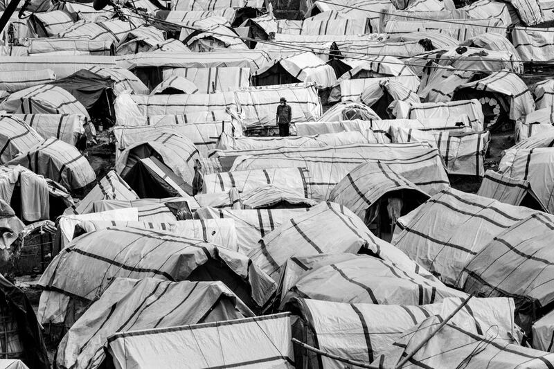 A man walks between hundreds of tents in a camp for displaced people on the outskirts of Kathmandu, Nepal, in 2015. Months after Nepal was hit by the earthquake, hundreds of thousands of people were still living in temporary shelters waiting for their homes to be rebuilt. Photo: Omar Havana/ Xposure Photo Festival