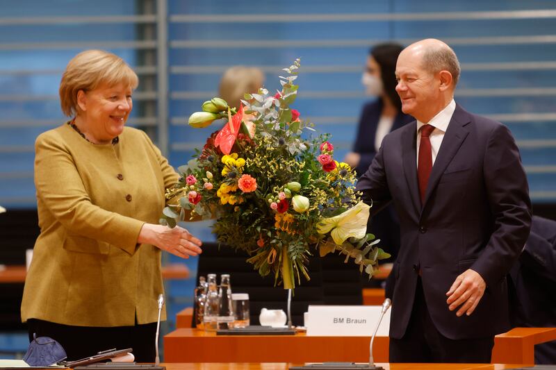 Ms Merkel receives a bouquet of flowers from Mr Scholz as she arrives for the cabinet meeting. EPA