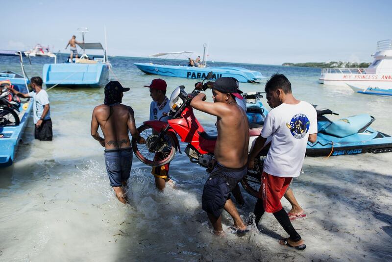 Employees of Milky Maming working next to rental speedboats, jetskis and a parasailing boat on the Philippine island of Boracay on April 25, 2018. Noel Celis / AFP