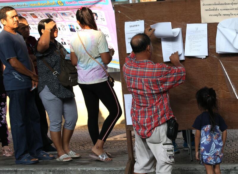 A Thai man with his child checks a list voter registration at a polling station in Bangkok. EPA