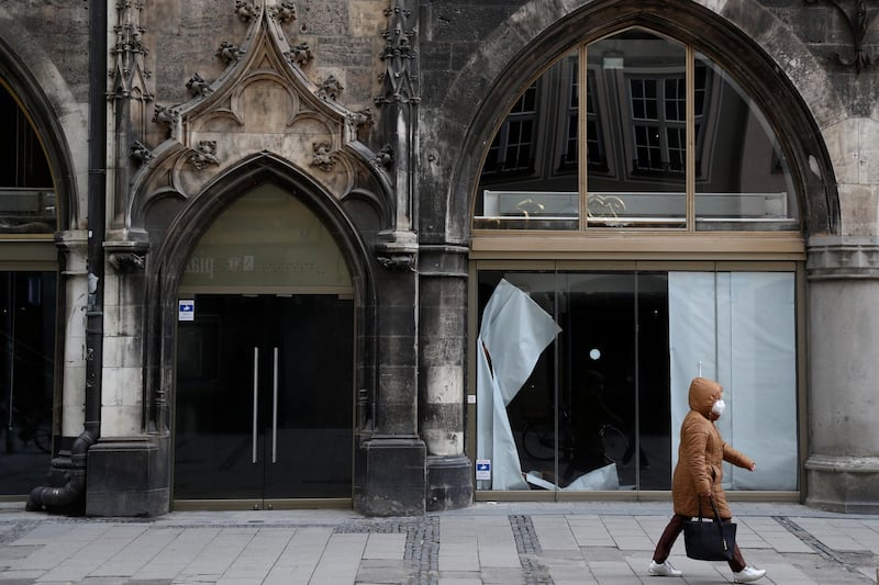A woman walks in front of a closed sportswear shop at the townhall in Munich, Germany, Tuesday, March 23, 2021. Germany extended its lockdown measures by another month and imposed several new restrictions, including largely shutting down public life over Easter, in an effort to drive down the rate of coronavirus infections. (AP Photo/Matthias Schrader)