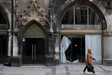 A woman walks past a closed sportswear shop in Munich, Germany. The global economy is expected to grow 6 per cent this year, compared with a previous forecast of 5.5 per cent, according to the IMF. Associated Press
