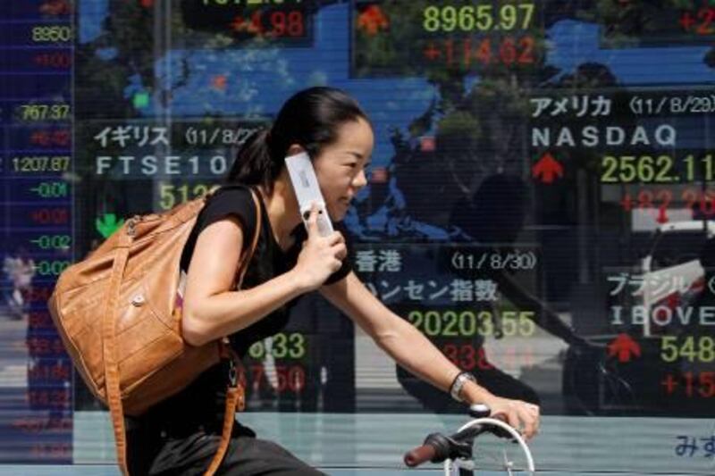 A woman cycles past an electric stock display of a securities firm in Tokyo, Tuesday, Aug. 30, 2011.  Asian-Pacific markets opened higher Tuesday, as investors took heart from strong consumer spending in the U.S. and a merger of two major banks in debt-stricken Greece. (AP Photo/Koji Sasahara) *** Local Caption ***  Japan World Markets.JPEG-0fcba.jpg