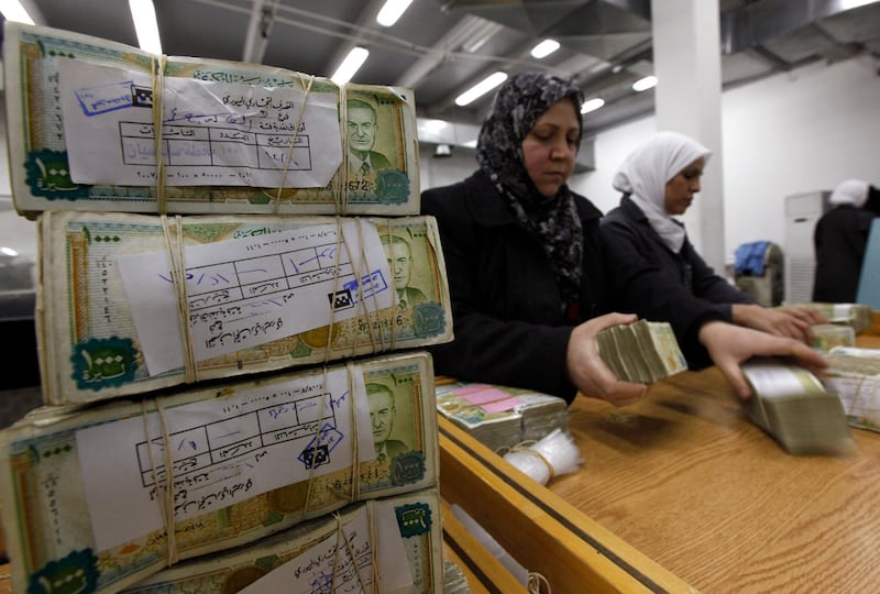 FILE - In this January 13, 2010 file photo, Syrian employees stack packets of Syrian currency in the Central Syrian Bank in, Damascus, Syria. In Syria nowadays, there is an impending fear that all doors are closing. After nearly a decade of war, the country is crumbling under the weight of years-long western sanctions, government corruption and infighting, a pandemic and an economic downslide made worse by the financial crisis in Lebanon, Syria's main link with the outside world. (AP Photo/Hussein Malla, File)