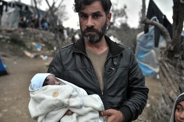 An Iraqi refugee holds his newborn in the overcrowded Moria camp on the Greek island of Lesbos where Covid-19 fears are at their most acute. AFP