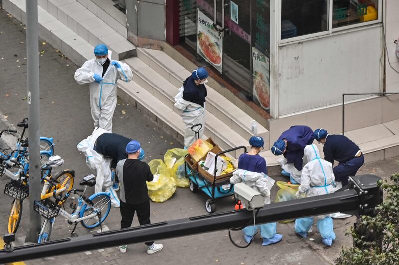 Workers remove their protective gear at the entrance of a neighbourhood. AFP