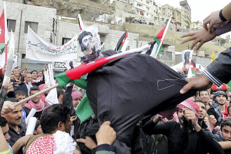 Jordanian protesters tear a dummy representing the leader of the Islamic State (IS) jihadist group, Abu Bakr al-Baghdadi (portrait), during a demonstration on February 6, 2015 in the capital Amman in solidarity with the pilot murdered by the extremist group. Thousands of people turned out after midday prayers and marched from the central al-Husseini mosque to Palm Park, about one kilometres (half a mile) away, in Amman in protest against IS. AFP PHOTO / KHALIL MAZRAAWI (Photo by KHALIL MAZRAAWI / AFP)
