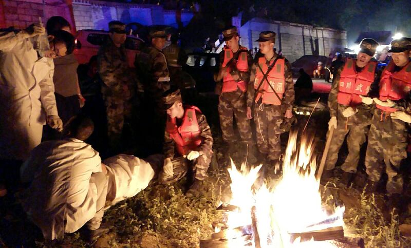 Rescuers tend to a survivor next to a fire after an earthquake in Jiuzhaigou in southwest China's Sichuan province. AFP