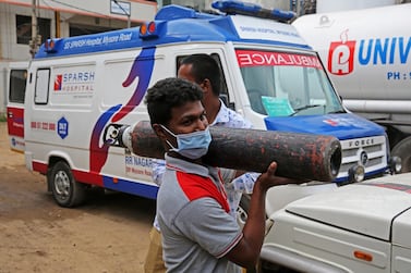A young Indian man carries an empty oxygen cylinder at a filling centre in Bangalore, India. EPA