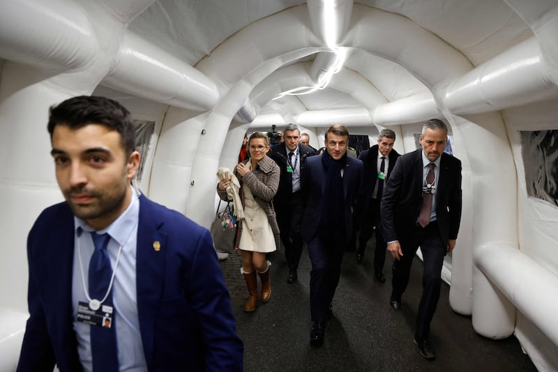 French President Emmanuel Macron (centre), flanked by delegation members, walks through an inflatable tunnel connecting venues at Davos. AFP