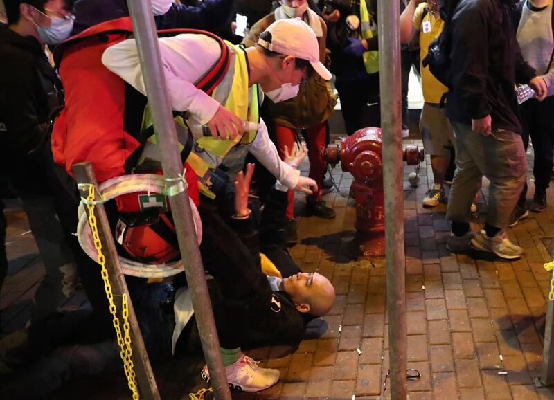 First aid volunteers try to protect a man who was fighting with a protester during a protest in Mong Kok, Hong Kong. AP Photo
