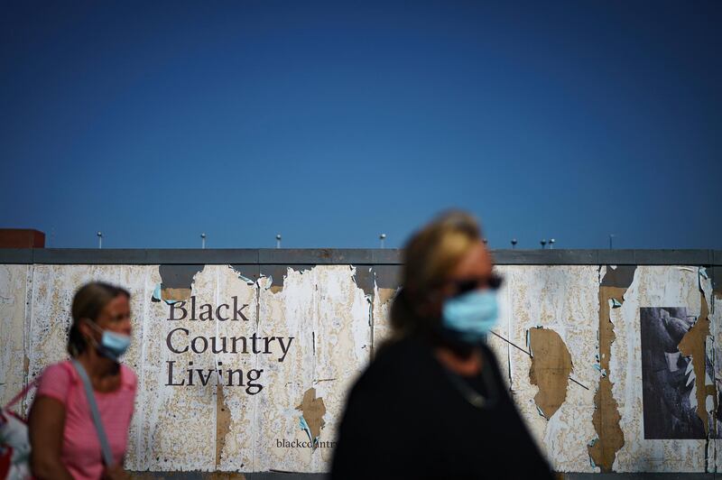 Shoppers walk past a dilapidated advertising hoarding in West Bromwich. Getty Images