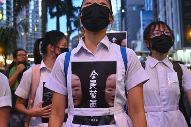 TOPSHOT - High school students chant slogans as they stick posters reading "all people masked" on their uniforms as protesters gather in the heart of Hong Kong's commercial district Central on October 4, 2019, after the government announced a ban on facemasks. Hong Kong's leader invoked colonial-era emergency powers on October 4 to ban protesters wearing face masks, but the move aimed at quelling months of unrest sparked immediate fresh rallies and vows to defy the new law. / AFP / Philip FONG