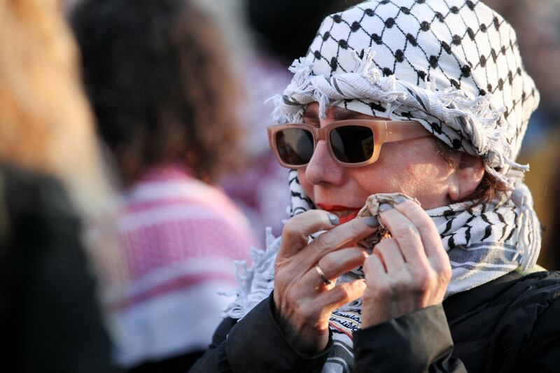 A woman wearing a Palestinian keffiyeh wipes tears from her face during the vigil for Mr Bushnell. Reuters