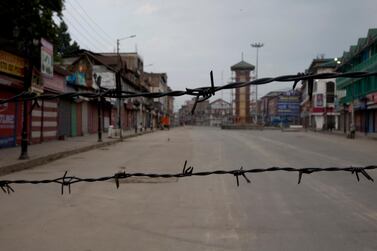A deserted street is seen through barbwire set up as a blockade during curfew in Srinagar, Indian controlled Kashmir. AP