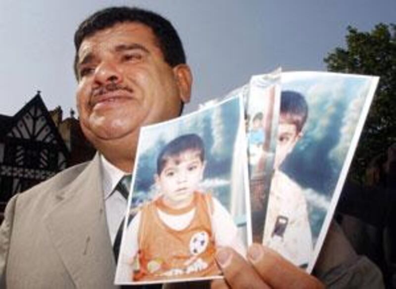 Daoud Mousa holds pictures of his grandchildren outside the High Court in London, where he is alleging that his son Baha died in the custody of British soldiers in southern Iraq last year.