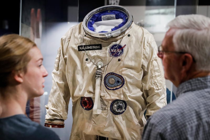 Visitors stand before the spacesuit worm by astronaut Neil Armstrong that was used on his Gemini VIII mission.