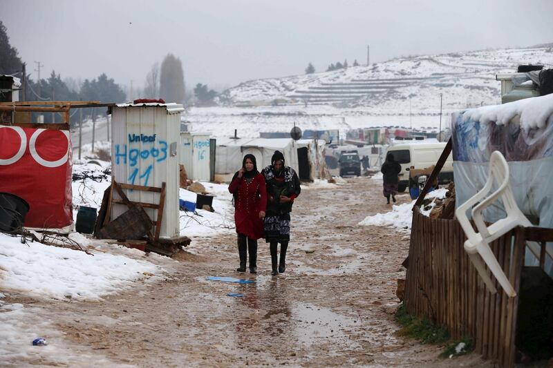 Two Syrian women from Raqqa walk through a Syrian refugee camp in the Bekaa Valley in Lebanon after the first heavy snow storm hit Lebanon, January 3, 2016.  REUTERS/Jamal Saidi - GF10000281622