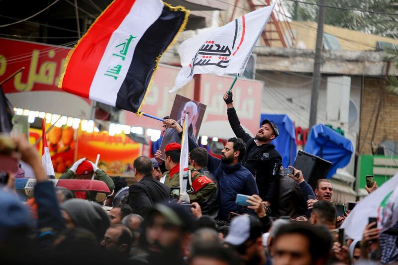 Mourners wave the national flag and the Hashed al-Shaabi flag as they carry the portrait of Iraqi paramilitary chief Abu Mahdi al-Muhandis during a funeral procession, for Muhandis and Iranian military commander Qassem Suleimani, in Kadhimiya, a Shiite pilgrimage district of Baghdad. AFP