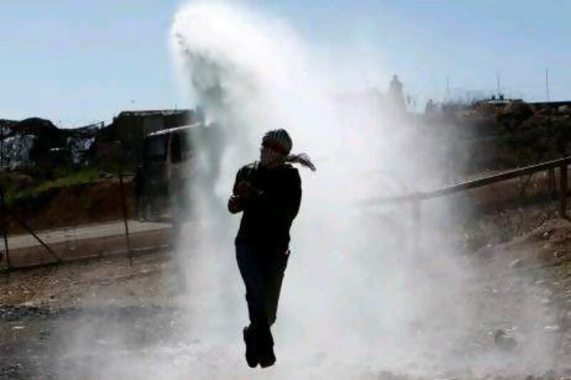 A Palestinian stone-thrower jumps as a water cannon containing ‘skunk’ spray is fired by Israeli security forces during clashes at a weekly protest in the occupied West Bank village of Bilin.