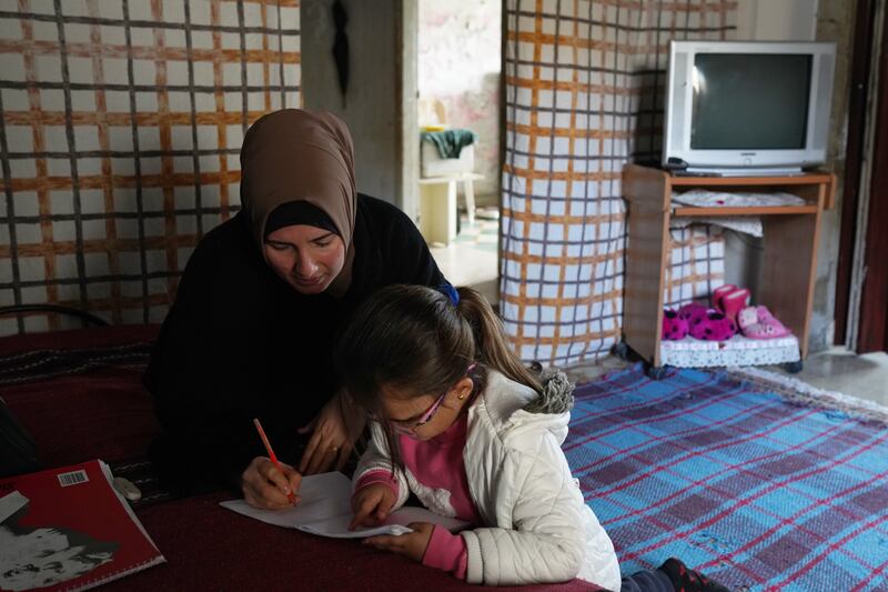 A mother helps her only daughter with writing at their home.