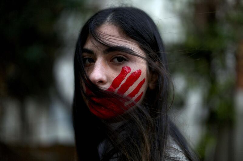 A Lebanese woman poses with her face painted with a red hand during a demonstration against sexual harassment, rape and domestic violence in the Lebanese capital Beirut on December 7, 2019. (Photo by Patrick BAZ / Abaad / AFP) / RESTRICTED TO EDITORIAL USE - MANDATORY CREDIT "AFP PHOTO / ABAAD / PATRICK BAZ - NO MARKETING NO ADVERTISING CAMPAIGNS - DISTRIBUTED AS A SERVICE TO CLIENTS -