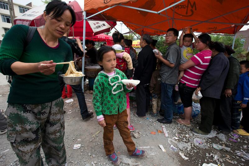 Residents queue up for a meal at the county seat of Lushan in southwestern China's Sichuan province, Sunday, April 21, 2013. Rescuers and relief teams struggled to rush supplies into the rural hills of China's Sichuan province Sunday after the earthquake prompted frightened survivors to spend a night in cars, tents and makeshift shelters. (AP Photo/Ng Han Guan) *** Local Caption ***  China Earthquake.JPEG-042b6.jpg