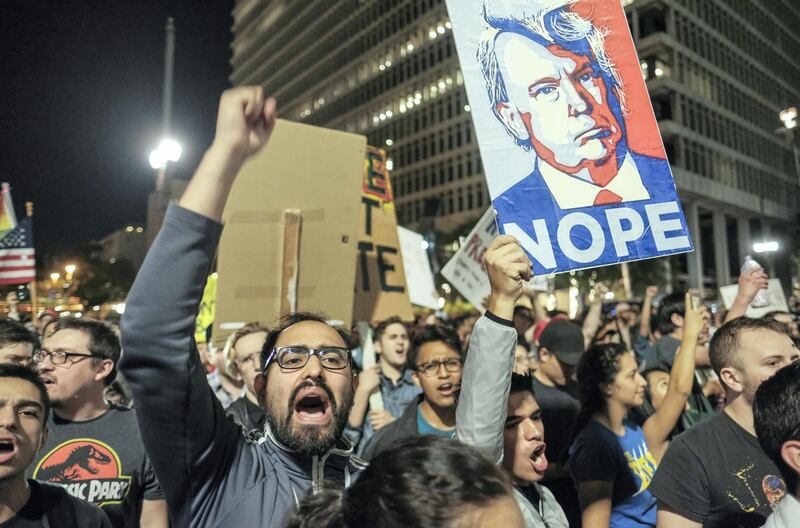 Demonstrators hold up placards to protest a day after President-elect Donald Trump's victory, during a rally outside Los Angeles City Hall in Los Angeles, California, on November 9, 2016. - Protesters burned a giant orange-haired head of Donald Trump in effigy, lit fires ins the streets and blocked traffic lanes late on November 9 as rage over the billionaire's election victory spilled onto the streets of US cities. From New York to Los Angeles, thousands of people in around 10 cities rallied against the president-elect a day after his stunning win, some carrying signs declaiming "Not our President" and "Love trumps hate." (Photo by RINGO CHIU / AFP)