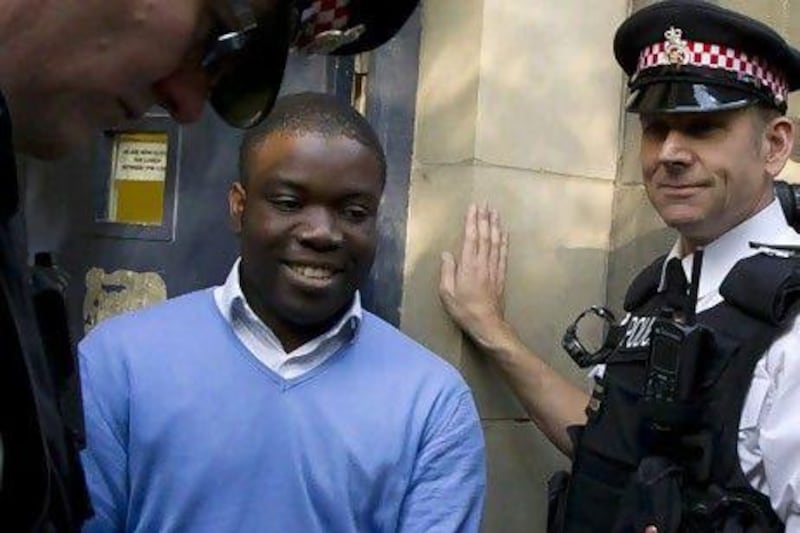 Kweku Adoboli, center, smiles as he head towards a security van in London. AP Photo