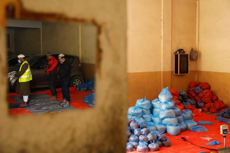 Nepalese Muslim men are seen reflected in a mirror as they pray next to sacks of food to distribute to needy families, on the first day of the holy month of Ramadan, as mass prayers in places of worship are suspended due to concerns about the spread of the coronavirus disease (COVID-19), in Kathmandu, Nepal April 25, 2020. REUTERS/Navesh Chitrakar