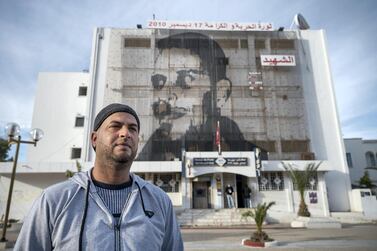 Kais Bouazizi stands beneath a giant mural to his cousin Mohammed Bouazizi in Sidi Bouzid, almost 10 years to the day since the events that led to the revolution. Peter Horton for The National
