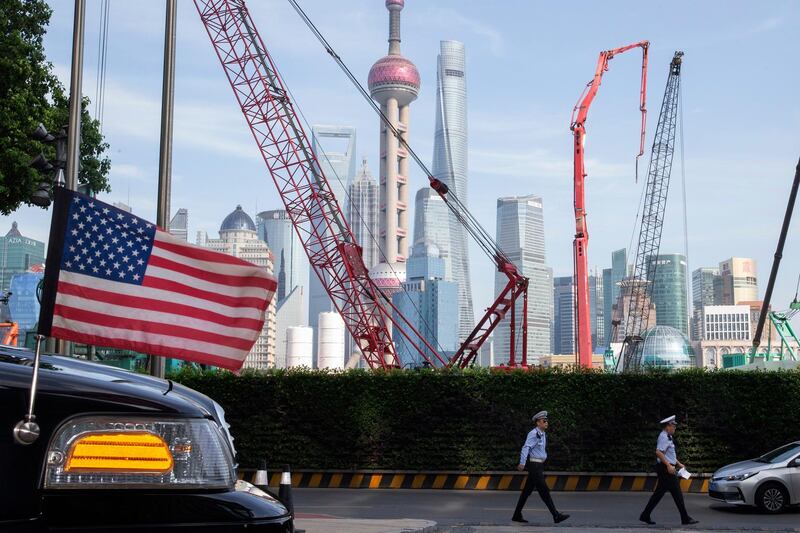 In this file photo taken Tuesday, July 30, 2019, Chinese traffic police officers walk by a U.S. flag on an embassy car outside a hotel in Shanghai where officials from both sides met for talks aimed at ending a tariff war. Both countries already have suffered heavy losses in a tariff war that erupted in 2018 over Beijing's technology ambitions and trade surplus. If talks on ending the dispute fail, the world could face downward pressure on trade at a time when the global economy is already reeling from the coronavirus pandemic. AP Photo